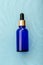 Blue glass dropper serum cosmetics products on blue water surface. Aqua collagen Dropper or hyaluron serum. Anti aging Face