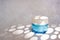 Blue glass moisturizer cream, shadows play on light concrete background. Cream jar mockup