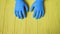 Blue gloved hands closeup on yellow wooden table. Call for hand disinfection. Stop coronavirus concept. Using