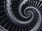 Blue gray industrial air craft turbine blades spiral background pattern distorted by three coils. Metal turbine wings repetitive b
