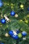 Blue and green balls on a faux christmas tree close and a glowing garland up