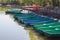 Blue and green boats at the pier of a large, urban pond