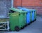 Blue and green mobile garbage containers in the yard of an apartment building