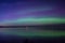 Blue green and purple aurora borealis reflected over a lake