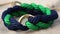 a blue and green rope bracelet with a gold ring on a white cloth background with a gold ring in the middle of the bracelet and a