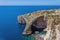 Blue Grotto rock cliff arch in Malta, aerial view from the Mediterranean Sea to the island