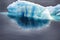 Blue growler (piece of iceberg) with reflection in calm water