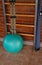 A blue gymnastic ball next to a wooden sports ladder.