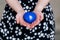 Blue heart in the hands of a woman in a polka dot dress