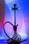 Blue hookah with black rubber tube and blue and white flask on interesting colorful background.