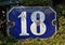 A blue house number plaque, showing the number eighteen