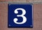 A blue house number plaque, showing the number three, number 3