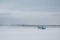 A blue hovercraft rushes along the snowy Volga River. A snow blizzard rises about her