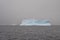 Blue iceberg in Antarctic sea on a grey cloudy day
