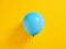 Blue inflated balloon on yellow background