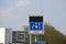 Blue information sign for the directions on Motorway A20 merging from 3 to 2 lanes on the road