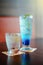 Blue itallian soda iced and drinking water in a glass on wood table, selective focus on green leaf, filtered image