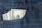 Blue jeans pocket with hundred dollars banknotes