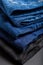 Blue jeans trousers stack textile texture fabric background. Stack of variety blue jeans, denim jean textiles on black