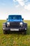 Blue Jeep Wrangler Rubicon Unlimited in wild tulip field near saltwater reservoir lake Manych-Gudilo