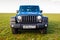 Blue Jeep Wrangler Rubicon Unlimited in wild tulip field near saltwater reservoir lake Manych-Gudilo