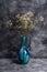 Blue jug vase with bulk gypsophila dried white flowers on dark textured stone background