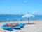 Blue kayaks, orange life jakets and white beach umbrella