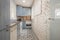 Blue kitchen cabinets with wood grain and white appliances, an exposed white brick wall and hydraulic tile floor