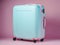 A blue large suitcase on a soft pink background. A symbol of travel and vacation