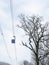 Blue lift rides cable car over snowy forest during snowfall.