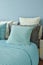 Blue, light blue and beige pillows on bed in blue wall bedroom