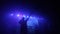 Blue light. The silhouette of a guy singing on stage. A raised up hand. A music group performing at a concert. Worship