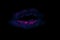 Blue lips with flowing luminous pink lipstick prints on black background surface