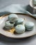 Blue macaroons on a gold plate on a gray background.