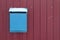 Blue mailbox hangs on a burgundy fence