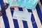 Blue medical protective mask, sunglasses and swim shorts on striped texture towel. Modern reality and relaxing on the beach during