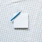Blue memo pad with colored pencil on blue check pattern fabric background