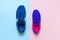 Blue mens and violet-pink female sneakers on pastel pink and blue background flat lay top view with copy space. Sports shoes, fitn