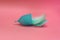 Blue Menstrual cup with blue feathers on pink background. Alternative feminine hygiene product during the period. Women health