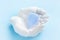 Blue menstrual cup in decorative plaster hands on blue background. Female intimate hygiene. Women health concept, eco