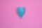 Blue menstrual cup on pink background. feminine hygiene during period time, top view