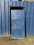 Blue metal hangar, door removed from its hinges and leaned against the entrance