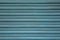 A blue metal jalousie with horizontal lines. paint stains on the surface.