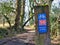 A blue metal sign on a wooden post shows the route of UK National Cycle Network route 56