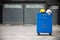 Blue metal tool cabinet with safety helmets, glove, document pad on the cabinet with garage background. Automobile repair service