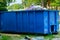Blue metal waste container with building debris
