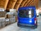 A blue minibus in a warehouse for industrial equipment and materials. Concept: delivery, logistics, incoterms dap, dpp terms of