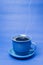 Blue mug with steaming hot coffee. Soft smoke. Blue background.