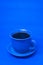 Blue mug with steaming hot coffee. Soft smoke. Blue background.