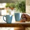 Blue mugs with hot drink in male hands.